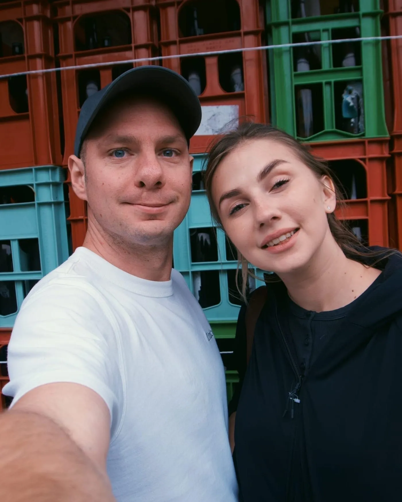 Jason and Polina in front of stacked crates of empty bottles