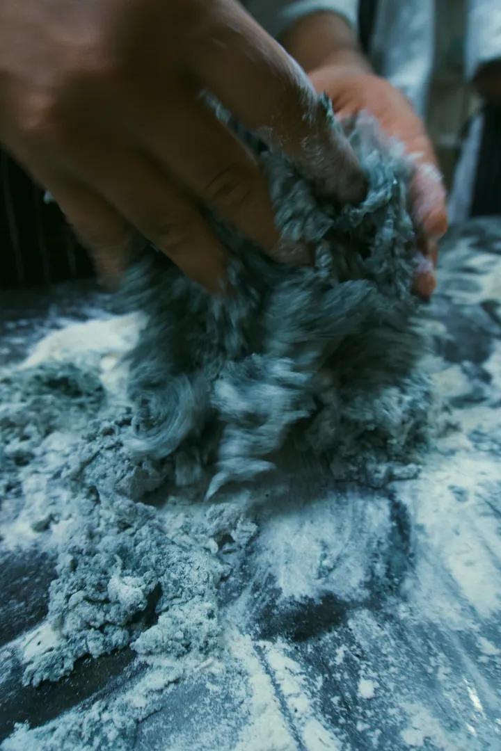 Hands kneading dark dough on a floured counter in Bengaluru