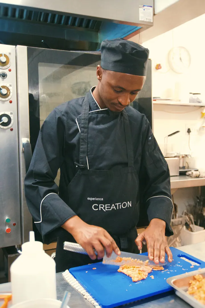 A Creation Wines chef chopping ingredients on a blue board