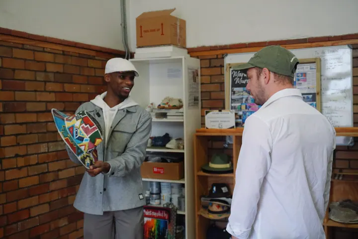 Jason talking with a man holding a brightly patterned woven piece during a local visit