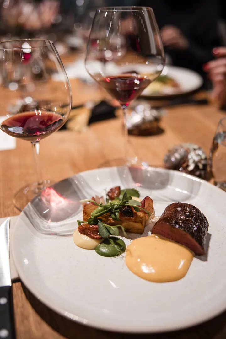 A plated duck course served beside Creation Wines glasses