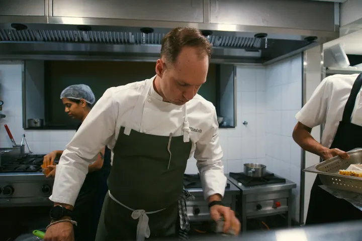 Jason cooking at the stove with chefs at The Leela Hyderabad