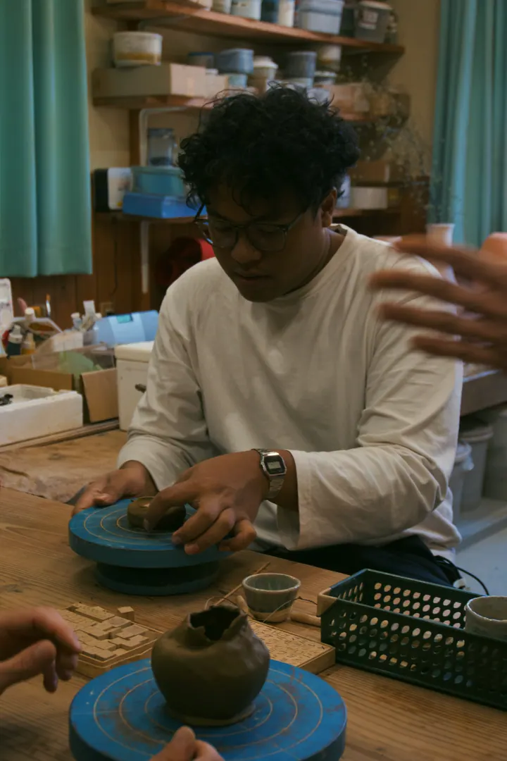 A potter shaping a small vessel at the wheel in Yunotsu