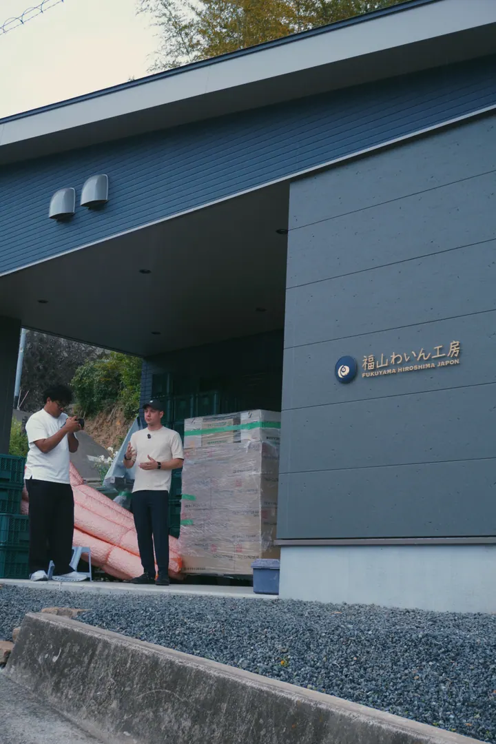 Visitors talking outside a dark-clad winery building in Japan