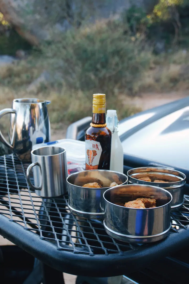A tray of cups and drinks on a safari vehicle during a stop in the bush