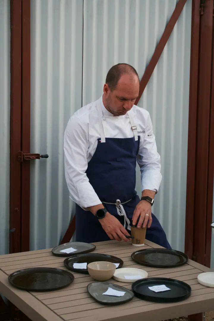 Jason looking over bowls and plates on a table at Kruger Shalati