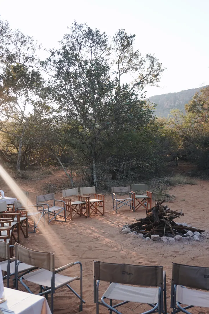 Wooden tables and chairs arranged around a fire site in the bush