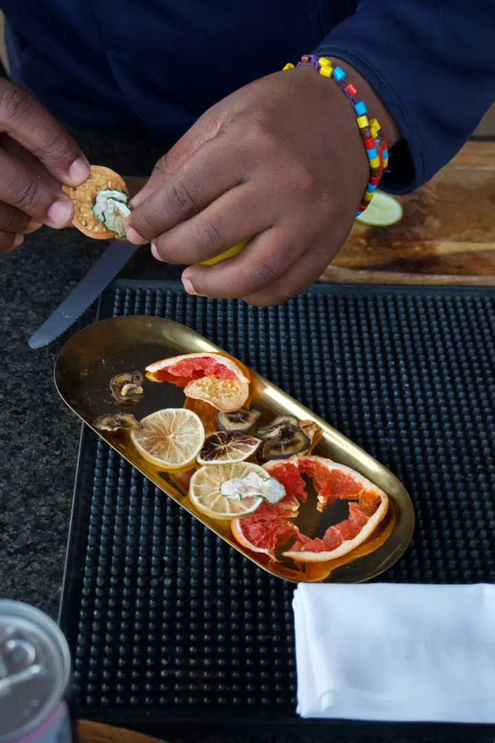 Hands squeezing citrus over a tray of food at Few & Far