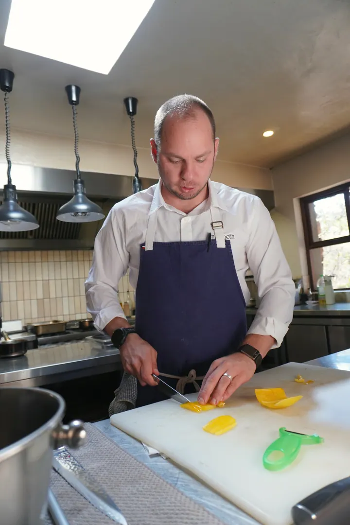 Jason slicing vegetables at the kitchen counter at Few & Far Luvhondo