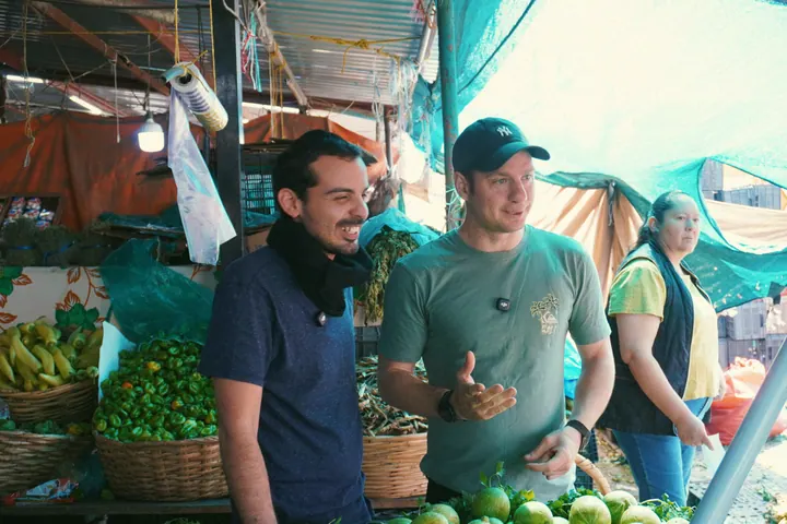 Jason and Travis talking at a produce stall before the barbacoa visit