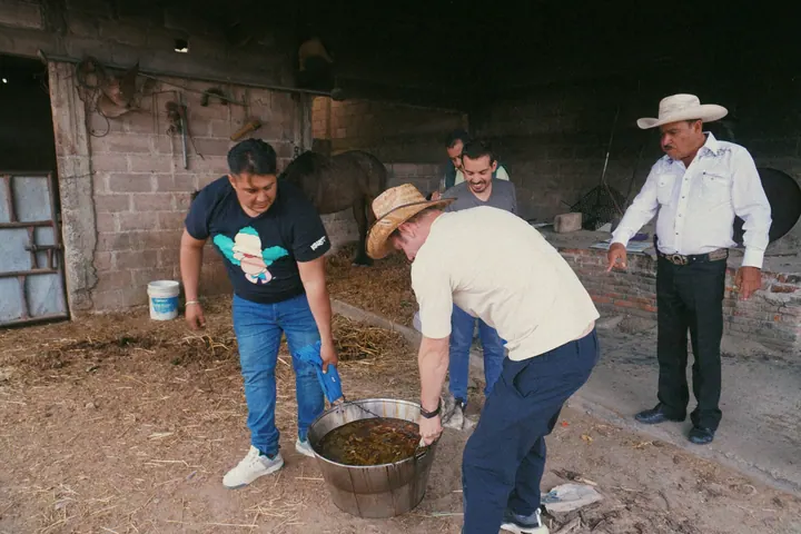 Members of the family lifting a large pot together beside the cooking area