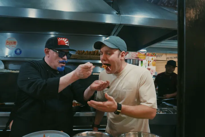 A chef offering Jason a bite of food at a Mexico City market counter