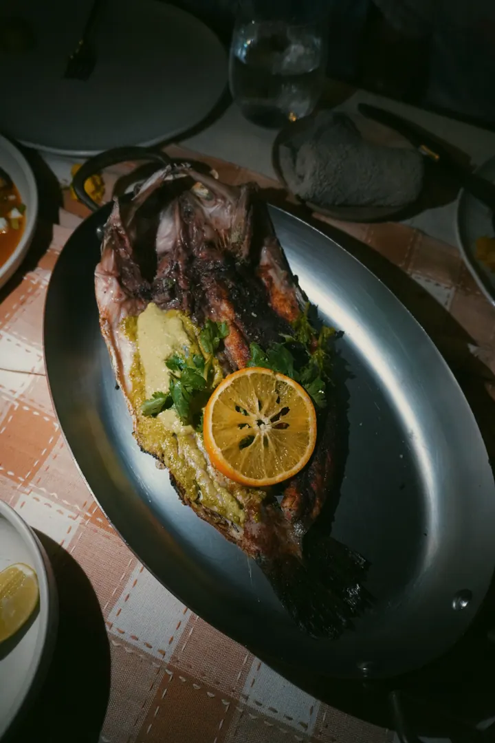 A whole cooked fish served with sliced citrus and herbs in Sumba